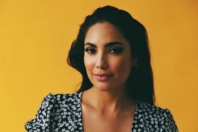 Headshot of Hispanic woman looking at camera in yellow room, copy space