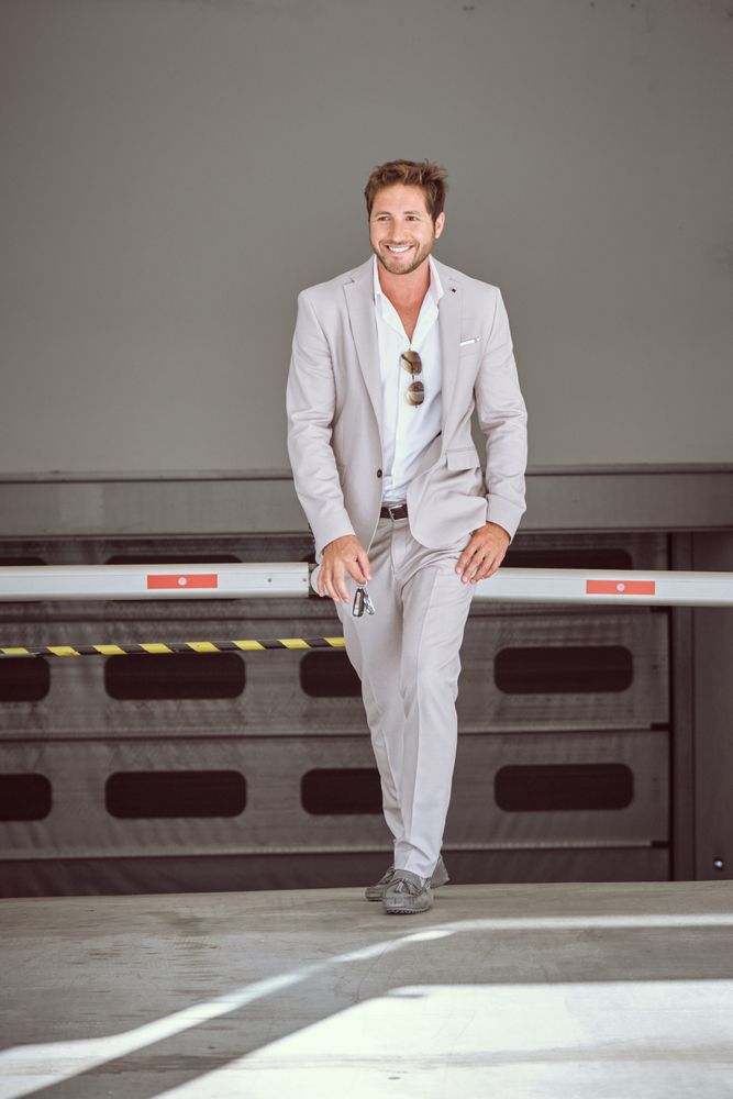 Confident businessman in suit walking against white fence