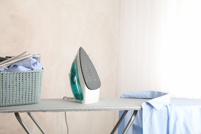 Iron and clean laundry on ironing board, space for text