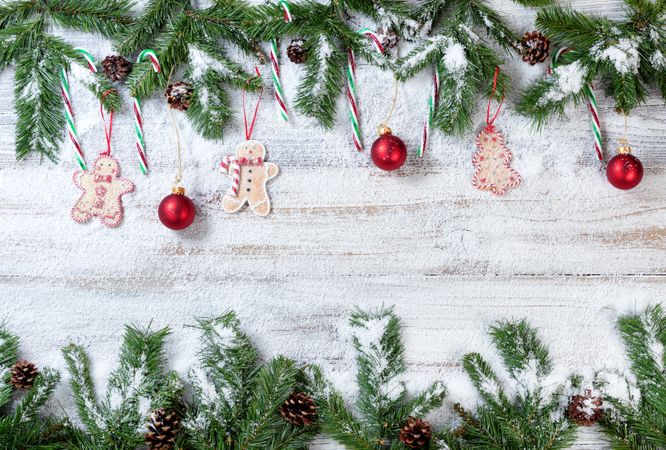 Snowy Christmas branches with associated ornaments on rustic wooden background