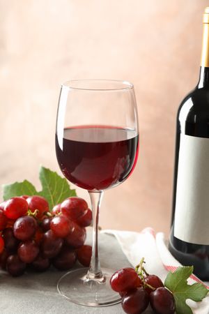 Grape, bottle and glass with wine on grey background, space for text