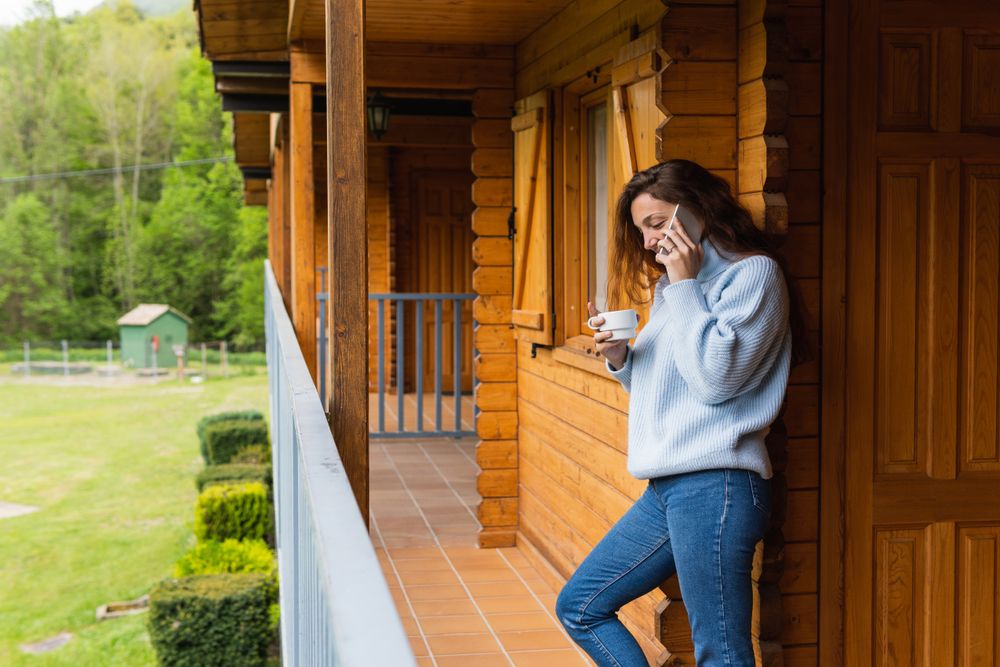 Content woman talking on smartphone on terrace of house