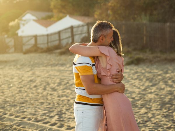 Laughing couple hugging on sandy beach