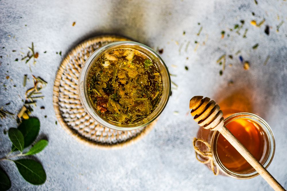 Top view of floral tea in glass with honey pot and dipper
