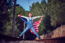 Excited boy with American flag on railway