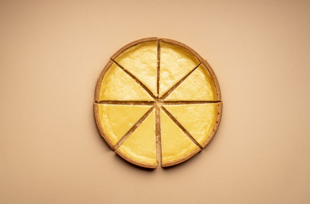 Cheesecake cut in 8 equal slices on a brown table