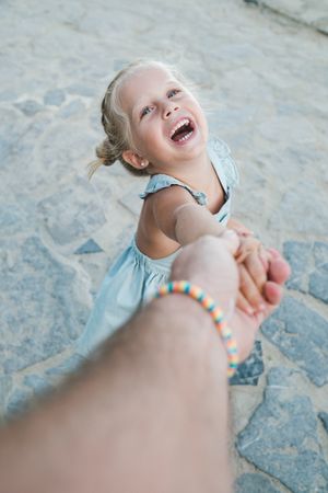 Excited girl holding hand of parent wile walking on street