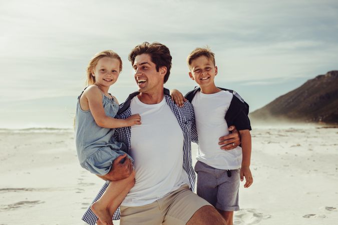 Happy man with his children on the beach