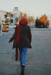 Back view of woman in brown coat and blue denim jeans running on gray asphalt road 0Pw3Nb