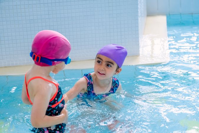 girls in hat smiling and swimming in pool in water park