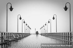 Silhouette of two people walking on bridge under umbrella 4OZaa5