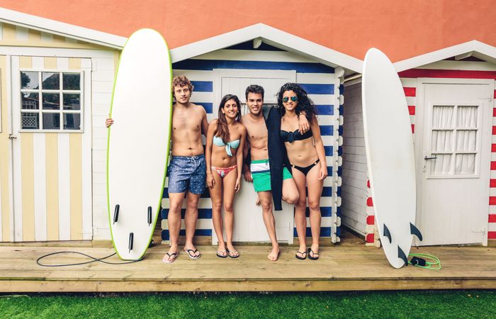 Group of people in swimsuits standing with surfboards