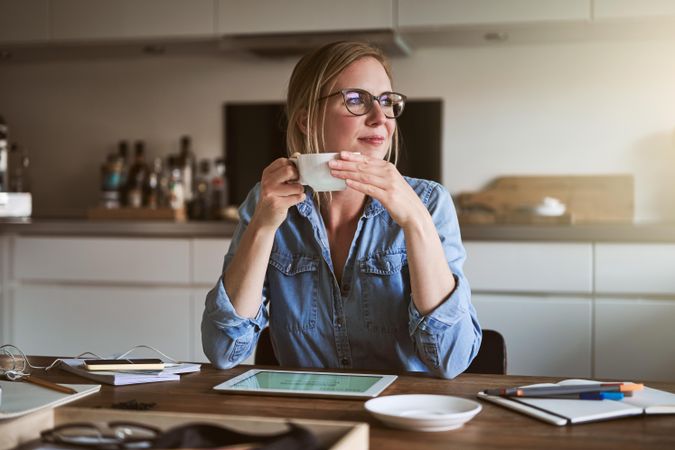 Woman with notebook and tablet thinking with coffee in hand