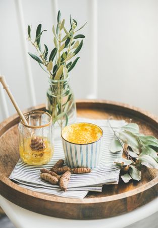 Morning turmeric latte in ceramic cup with honey in glass