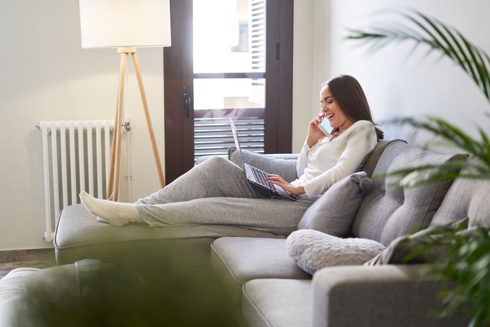 Smiling woman browsing on laptop and sitting on settee