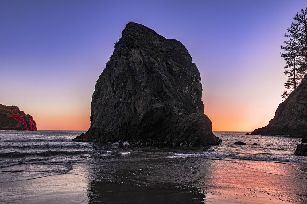 Large rock on the west coast at dusk with beautiful purple orange sky