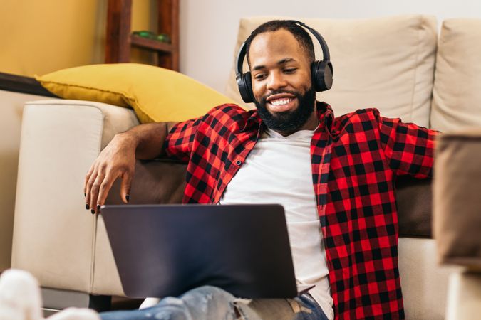 Black man in casual clothes using laptop at home.