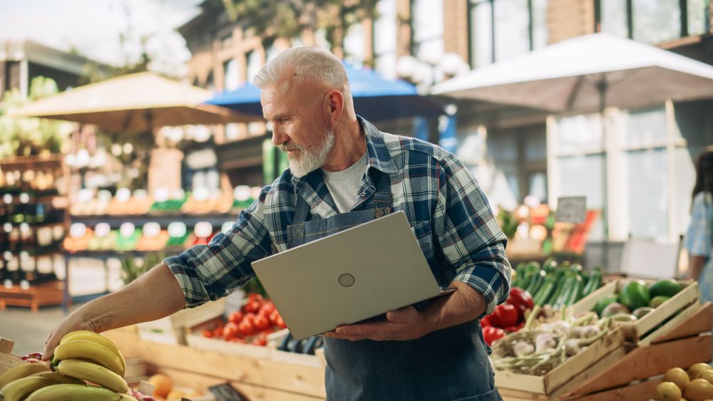 Successful Adult Male Farmer Working on a Laptop Computer, Checking Online Inventory List