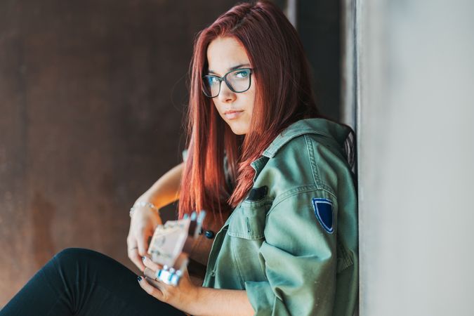 Romantic woman playing guitar leaning on wall