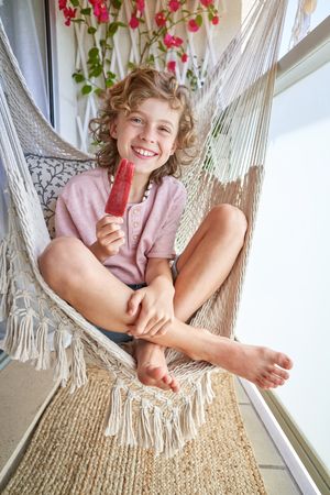 Boy with ice cream sitting in hammock