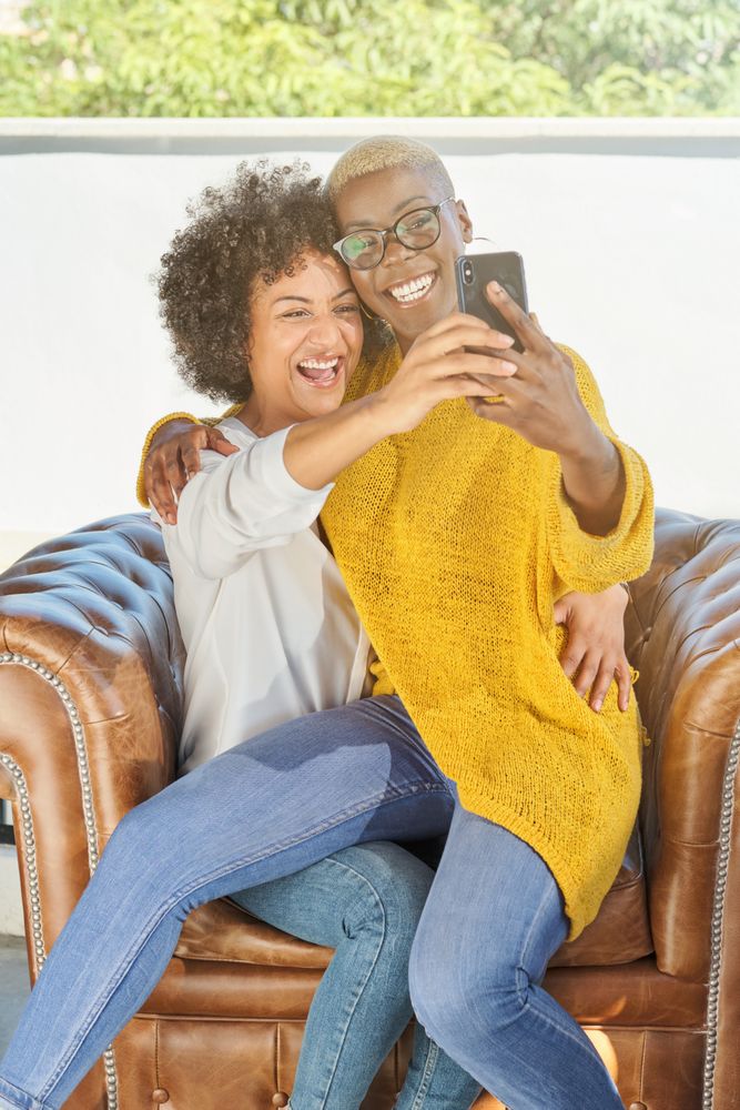 Diverse lesbian women hugging and taking selfie
