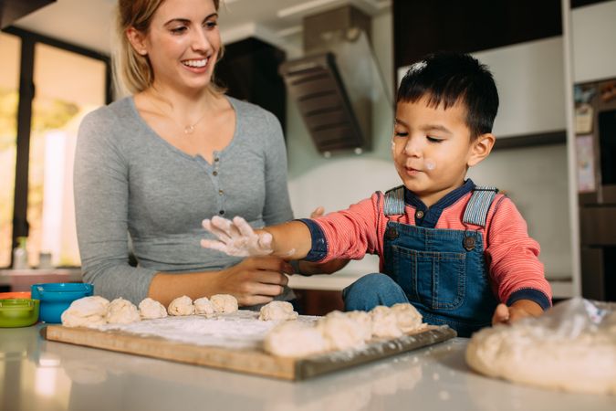 Little boy and mother having fun making cookies with mother in kitchen