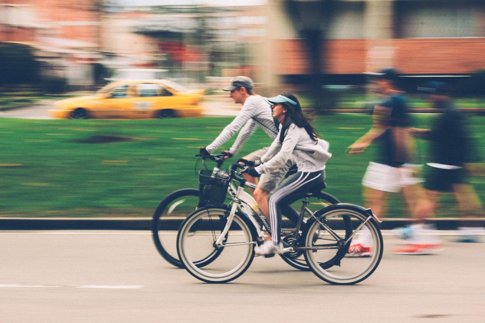 Man and woman riding bicycles in park during daytime