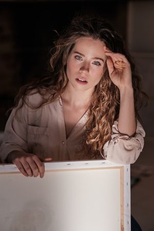 Pensive female artist with canvas