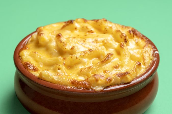 Mac and cheese bowl close-up, isolated on a green background