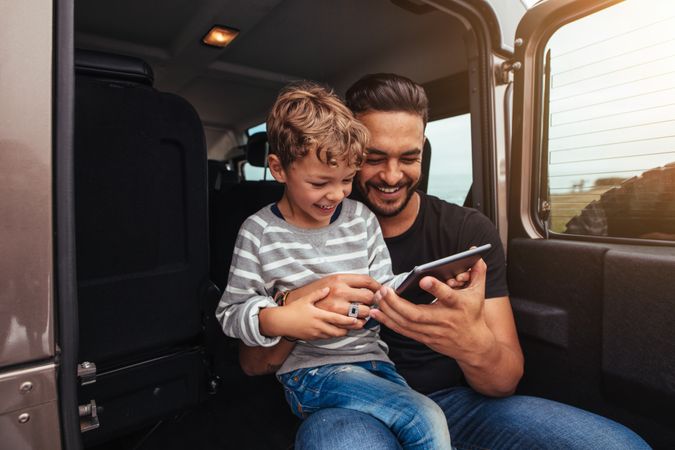 Handsome man with little boy holding digital tablet on road trip