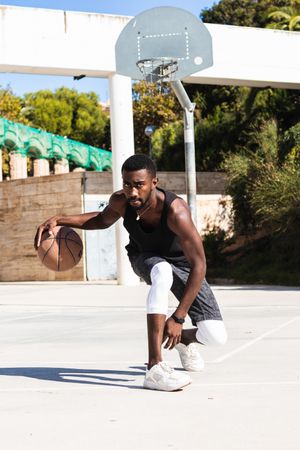 Black man playing basketball on sports ground