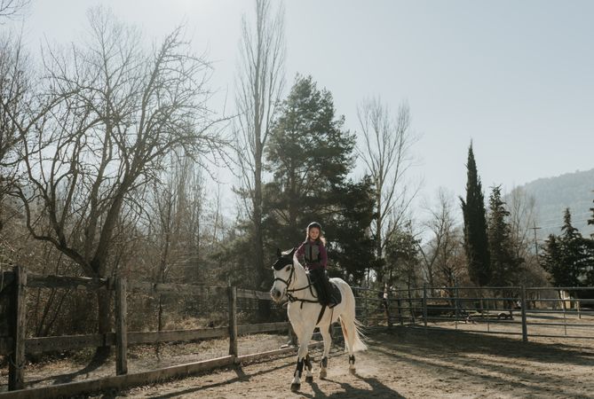Little girl riding horse in enclosure