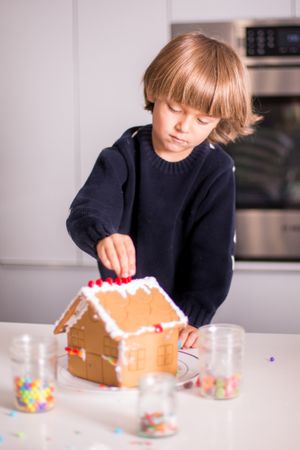 Boy making gingerbread house in the kitchen