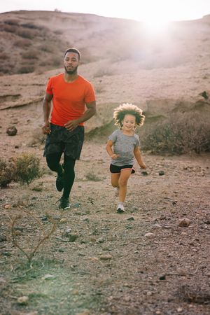 Black man jogging with toddler on nature