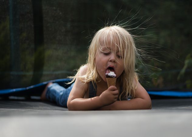 Young girl sitting on the ground eating ice cream
