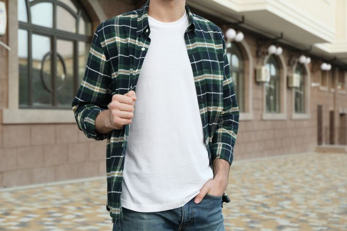 Men in t-shirt and checkered shirt against building, copy space