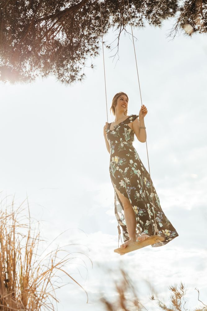 Happy woman enjoying on a swing at sunset
