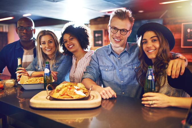 Group of friends sitting at the bar with beer and food