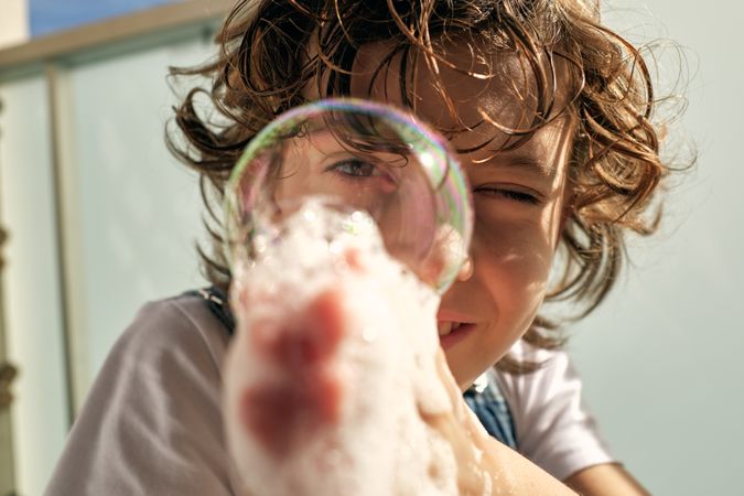 Happy kid blowing bubbles on balcony