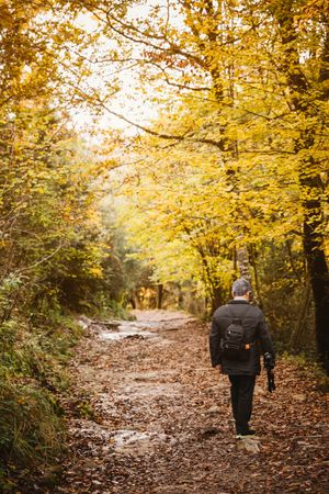 Anonymous photographer walking in autumn park