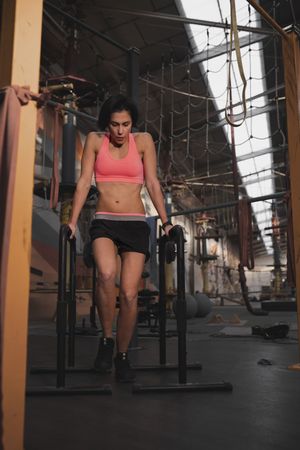 Athletic woman training on parallel bars in gym
