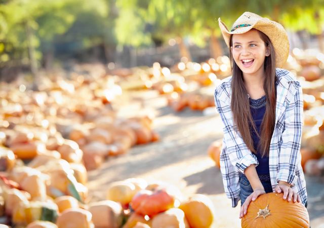 Girl Wearing Cowboy Hat Enjoying The Pumpkin Patch on a Sunny Fall Day.