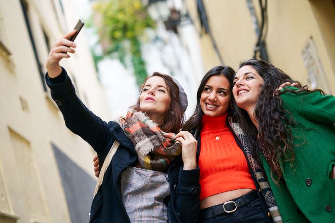 Three female friends dressed in fall clothes taking selfie
