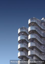Curves of a brutalist car park against a blue sky 0VjYv0