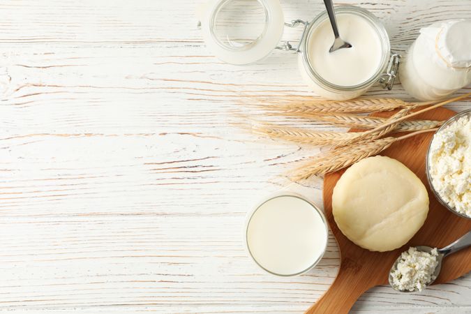Flat lay. Spikelets of wheat, dairy products and board on wood background