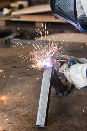 Crop master welding metal pieces at workbench