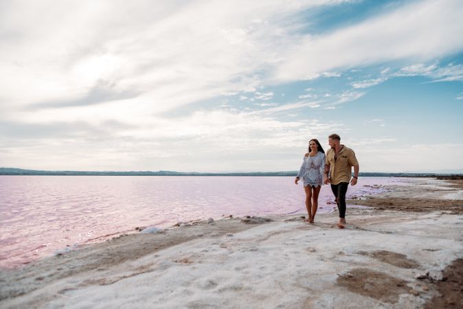 adorable couple walking on an amazing beach with pink water