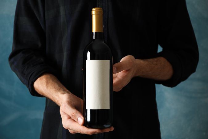 Man in shirt hold bottle of wine with empty space against blue background