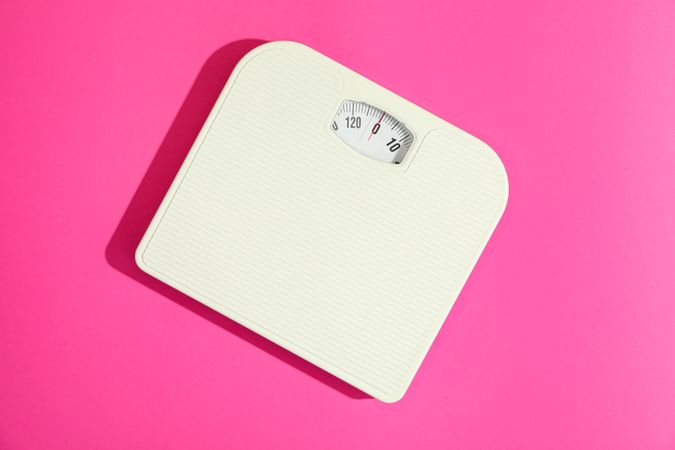weigh scales on pink background, space for text