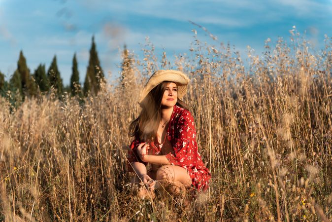 Happy dreamy woman sitting among high grass